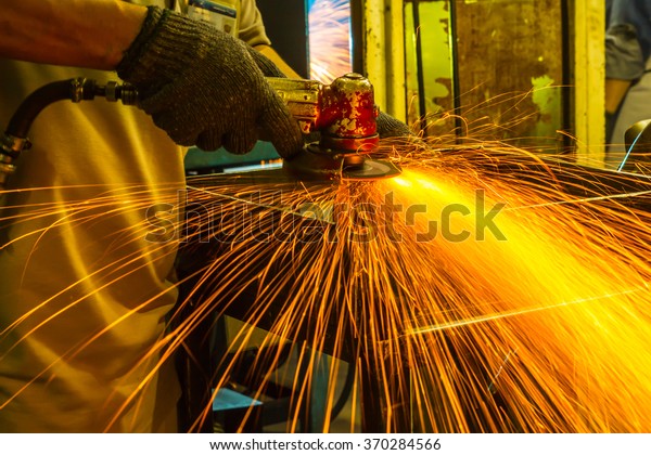 The worker\
grinding metal in manufacturing\
plant