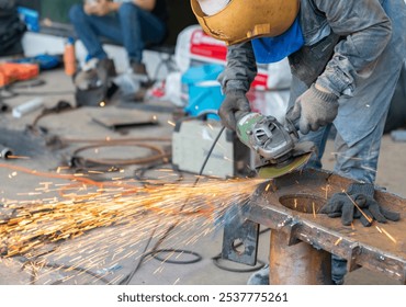 Worker grinding steel with an electric grinder in workshop.. - Powered by Shutterstock