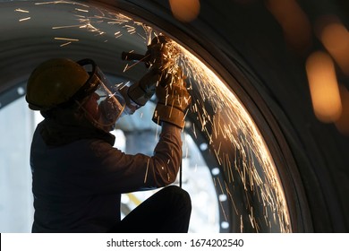 The worker is grinding steel material and weld metal with hand grinding machine from inside of large pipe. Grinding is an abrasive machining process that uses a grinding wheel as the cutting tool. - Powered by Shutterstock