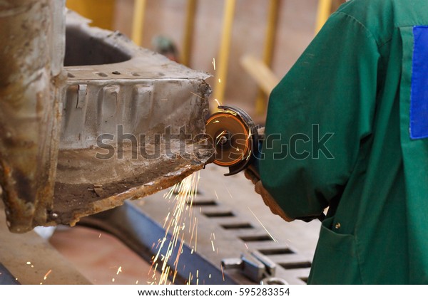 A worker grinds a car\
tool