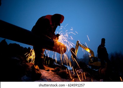 A worker grinds a pipe on the construction of a pipeline