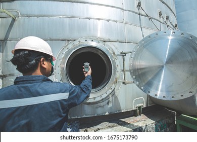 Worker hand holding gas detector inspection safety gas testing at front manhole stainless tank to work inside confined