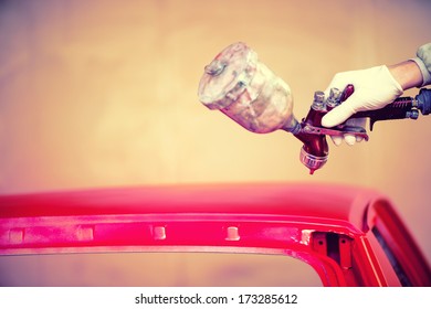 Worker Hand Painting A Red Hood Of Car In Auto Workshop