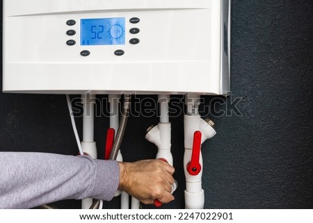 Worker hand remote or installing double-circuit gas boiler for winter home heating and water heating. Energy saving and heat conservation concept
