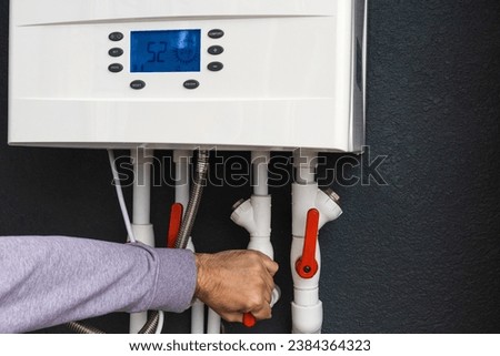 Worker hand remote or installing double-circuit gas boiler for winter home heating and water heating. Energy saving and heat conservation concept