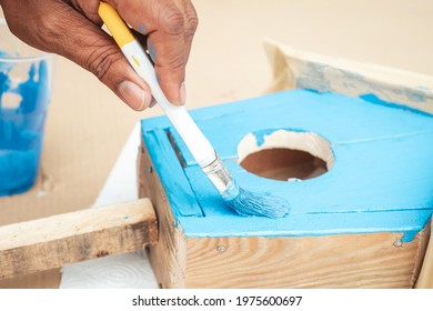 Worker hand using a paint brush with blue color. DIY carpenter wood work painting.