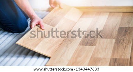 Worker hands installing timber laminate floor. Wooden floors house renovation with measure items.