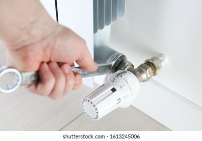 Worker hands repairing radiator with wrench. Close-up.Removing air from the radiator and fixing a heating problem.Dismantling and repair of a heating radiator in a house, apartment.Heating off. - Shutterstock ID 1613245006