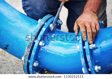 Worker hands screwing nuts on new drink water piping - close up