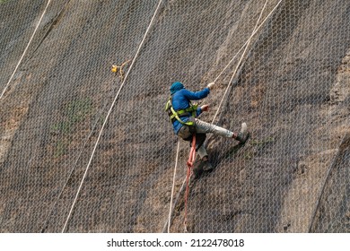 Worker At Heights With No Safety Helmet Is Climbing Up The Landslide Safety Net