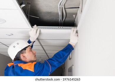 A Worker In A Helmet Finishes The Installation Of A False Ceiling, Side View