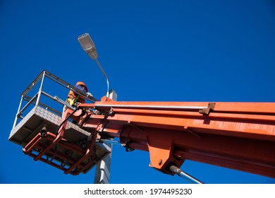 Worker With Helmet And Safety Protective Equipment Installs New Diode Lights. Worker In Lift Bucket Repair Light Pole. Modernization Of Street Lamps. 