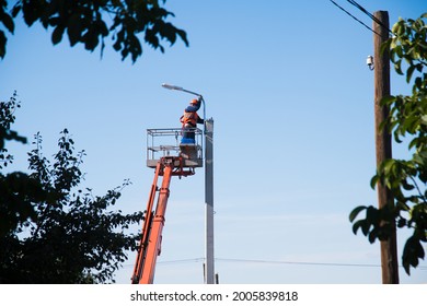 Worker With Helmet And Safety Protective Equipment Installs New Diode Lights. Worker In Lift Bucket Repair Light Pole. Modernization Of Street Lamps. 