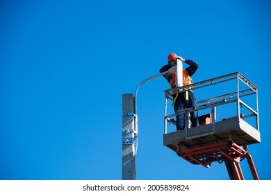 Worker With Helmet And Safety Protective Equipment Installs New Diode Lights. Worker In Lift Bucket Repair Light Pole. Modernization Of Street Lamps. 