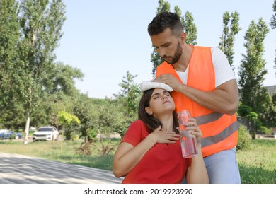 Worker Helping Woman On City Street. Suffering From Heat Stroke