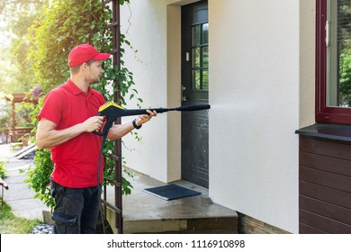 Worker With High Pressure Washer Cleaning House Facade