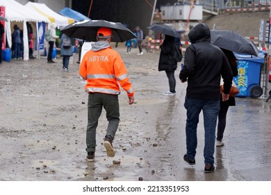 Worker With High Visible Jacket And Umbrella Of Federal Roads Office (FEDRO) At Open Day Of Highway Enclosure At City Of Zürich On A Rainy Day. Photo Taken October 1st, 2022, Zurich, Switzerland.