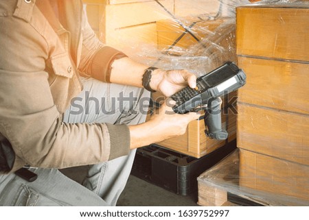 Worker holding barcode scanner his inspecting of product in storage warehouse.