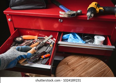 a worker holding a chisel with a draw full of tools in the background