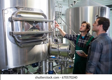 Worker holding digital tablet explaining to coworker at factory - Powered by Shutterstock