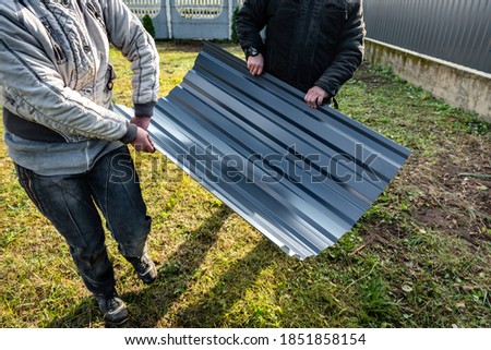 Worker holding metal sheet on grass background.