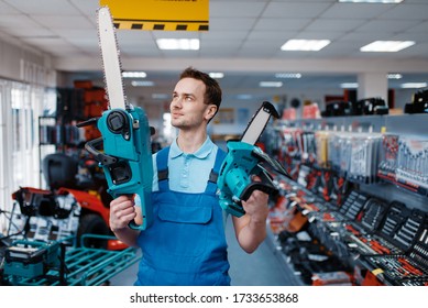 Worker Holds Big And Small Chainsaws In Tool Store