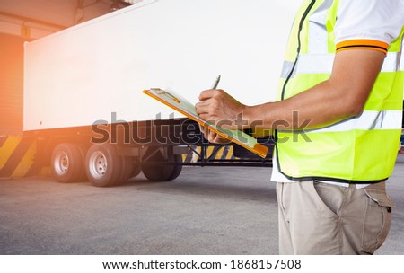 Worker Holds a Clipboard Checking the Loading Cargo Shipment at Dock Warehouse. Delivery Container Trucks. Distribution Warehouse. Freight Truck Logistics Transport 
