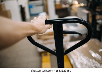 The Worker Holds The Handle Of The Manual Pallet Jack In The Warehouse