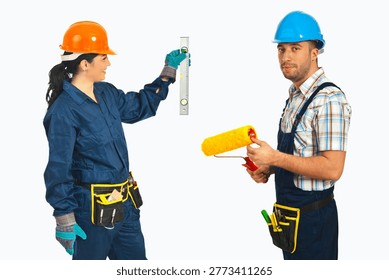 Worker holds level, checking wall height. Second worker holds paint roller, ready to work. Both wear safety gear, tool belts, gloves. Focused, cooperative team approach. Ideal for construction
