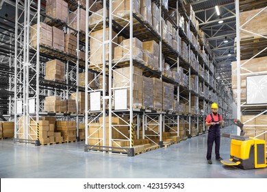 A Worker In A Huge Distribution Warehouse With High Shelves