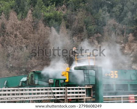 Worker hydro blasting on main deck of ship at shipyard.