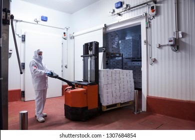 Worker With Hygienic Clothes Removing A Pallet Of Boxes From The Freezer Camera Of The Meat Cutting Room