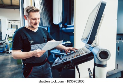 Worker in industrial workshop programming a cnc machine using keyboard