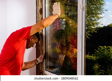 The worker inserts glass into the window frame, triple glazing of the plastic window, insulation and insulation.