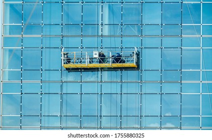 Worker Inspecting Glass Window Installation Of Tall Glass Exterior Office Building. Tall Glass Building Cleaning. Working At High Safety.