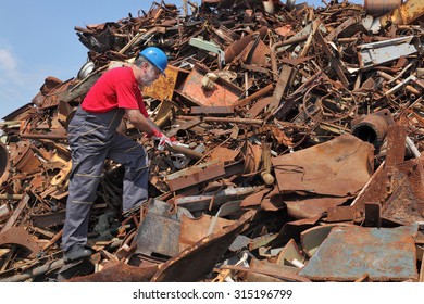 Worker inspecting heap of scrap metal ready for recycling - Powered by Shutterstock