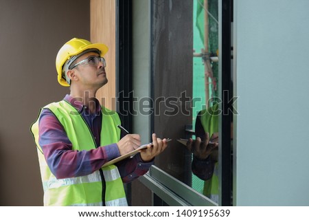 Worker, inspector, engineer is checking building structure around window with checklist in hand. Inspect and checking concept