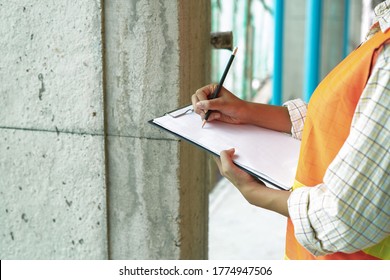 Worker inspector or engineer is quality checking audit and inspect the construction site building or house by using paper checklist on clipboard