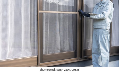 A worker inspects a screen and a sash window.