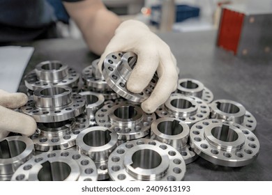 A worker inspects and sorts round parts with holes for assembling them into components and assemblies. - Powered by Shutterstock