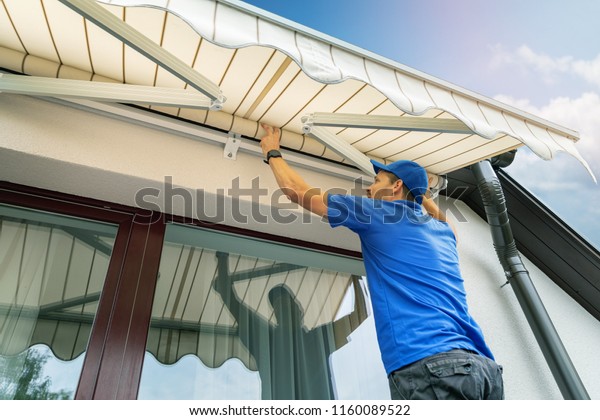 worker install an awning on the house wall over\
the terrace window
