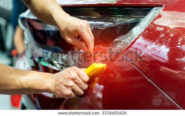 Worker\
install car paint protection film with\
spatula