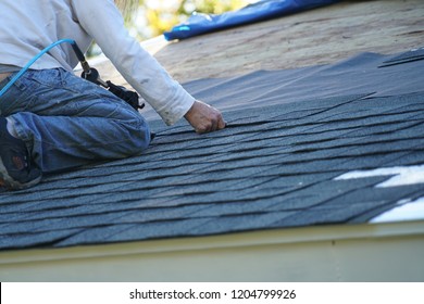 worker install new shingle on the roof of the house for roof repair