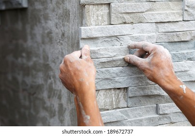 worker install stone wall surface with cement for house