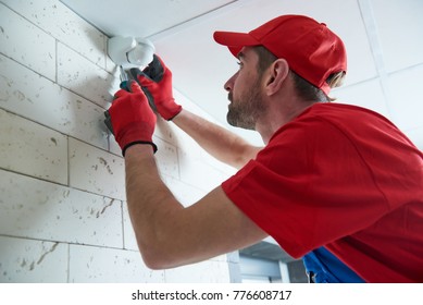 worker installing or adjusting motion sensor detector on the ceiling