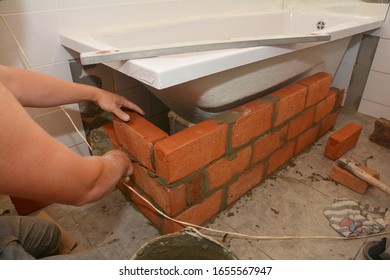 Worker Installing Bath Tub With Bricks Foundation In The House Bathroom