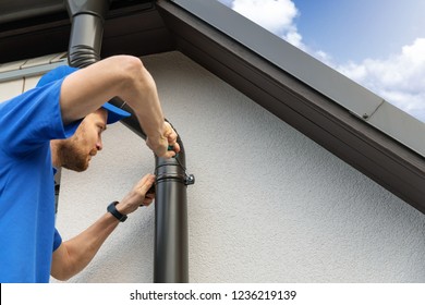 Worker Installing House Roof Gutter