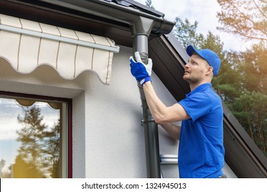 Worker Installing House Roof Rain Gutter System