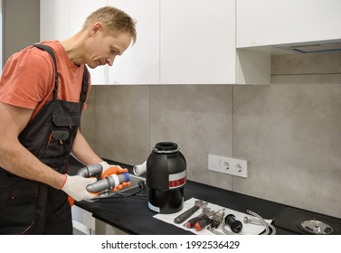 The Worker Is Installing A Household Waste Shredder For The Kitchen Sink.