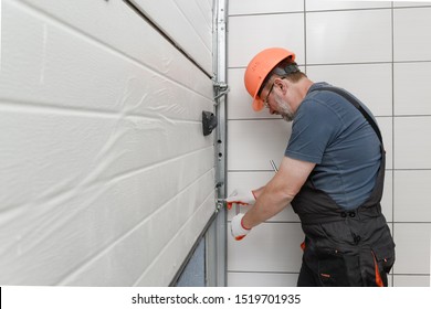 The worker is installing the lifting gates of the garage. - Powered by Shutterstock